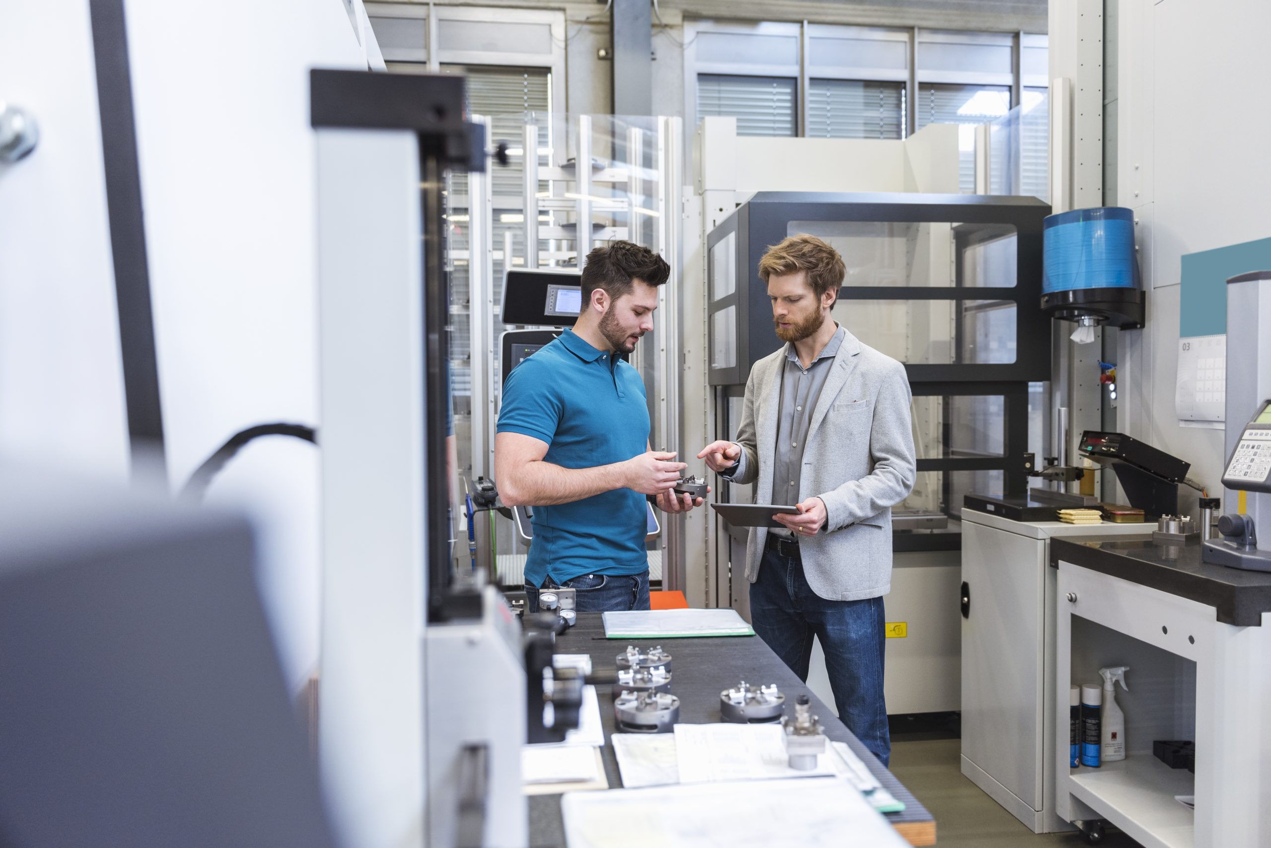 Two men with tablet talking in modern factory